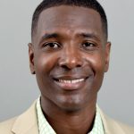 Scott Brooks, associate director of Global Sport Institute, headshot smiling in tan suit