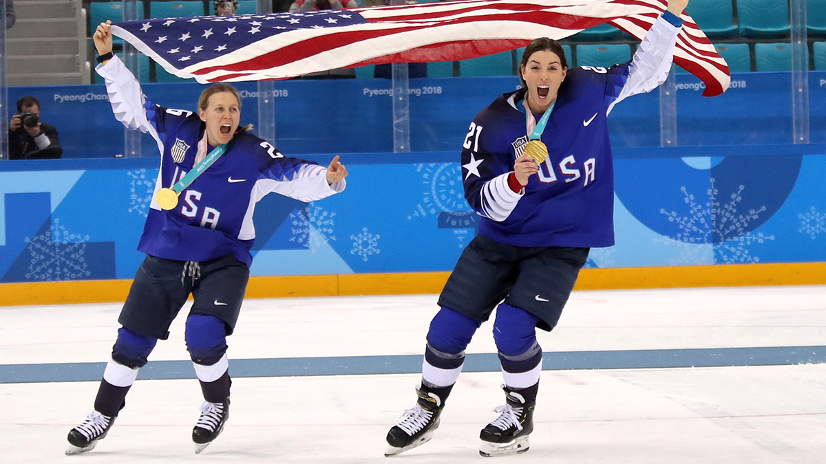 Kendall Coyne and Hilary Knight of the U.S. women's hockey team skating on ice rink with gold medals
