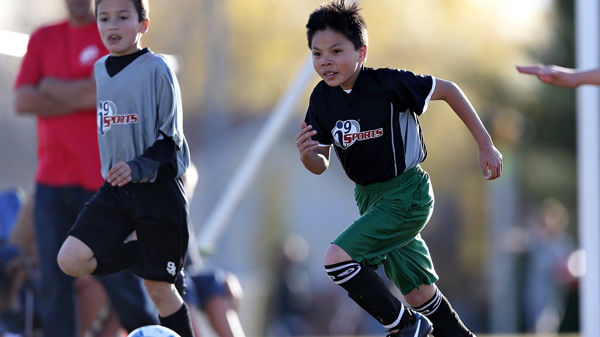 Two boys playing soccer in their i9 uniforms