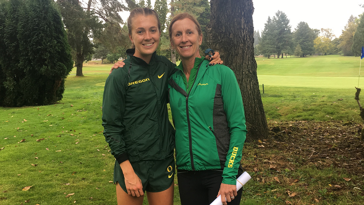 Katie and Lisa Rainsberger taking a photo on a golf course dressed in University of Oregon gear