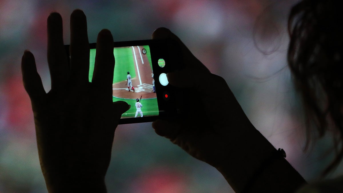 Fan taking a photo on phone during a 2017 baseball game