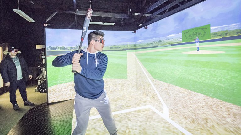 Boy in athletic clothes holding a baseball bat doing virtual reality baseball