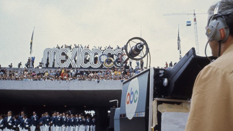 An ABC newscaster records athletes entering the stadium at the 1968 Olympics