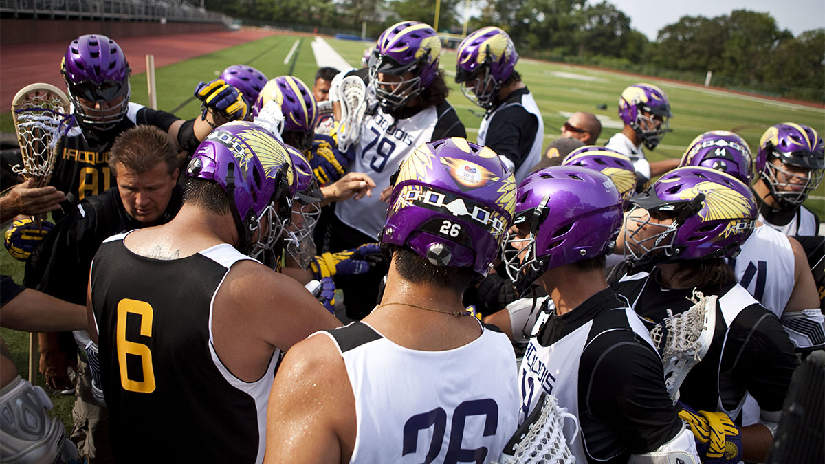 Lacrosse players with purple helmets in a huddle