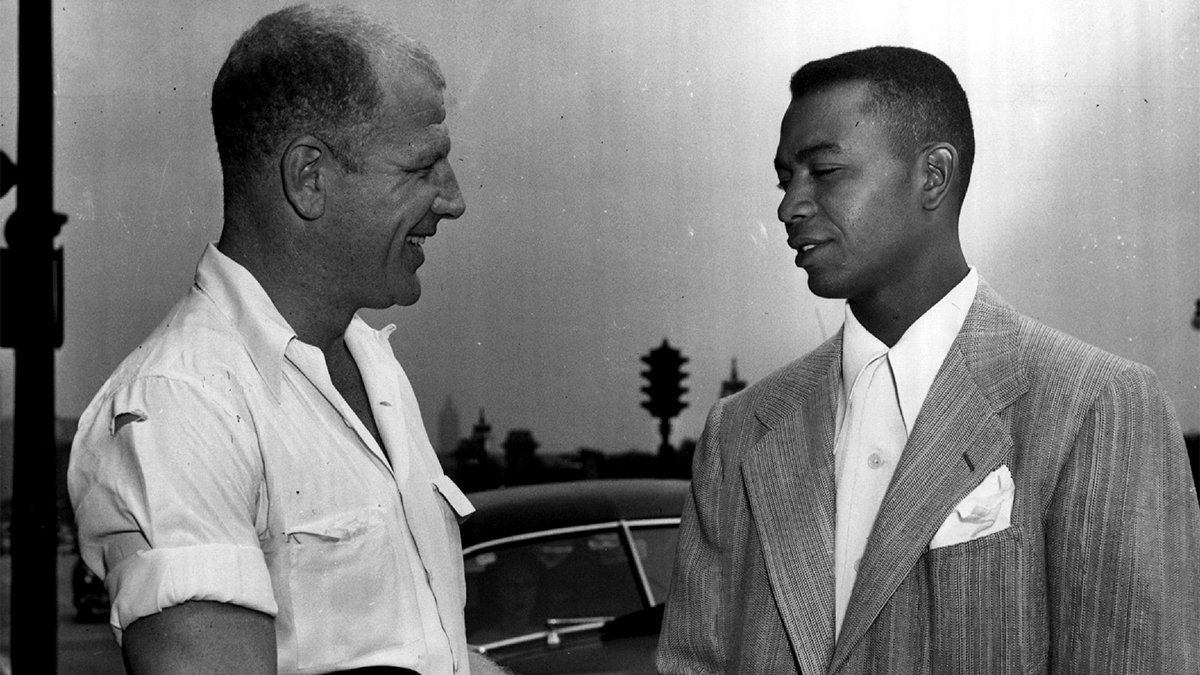 President Bill Veeck of the Cleveland Indians and the American league's first black player, Larry Doby smiling and speaking to each other.