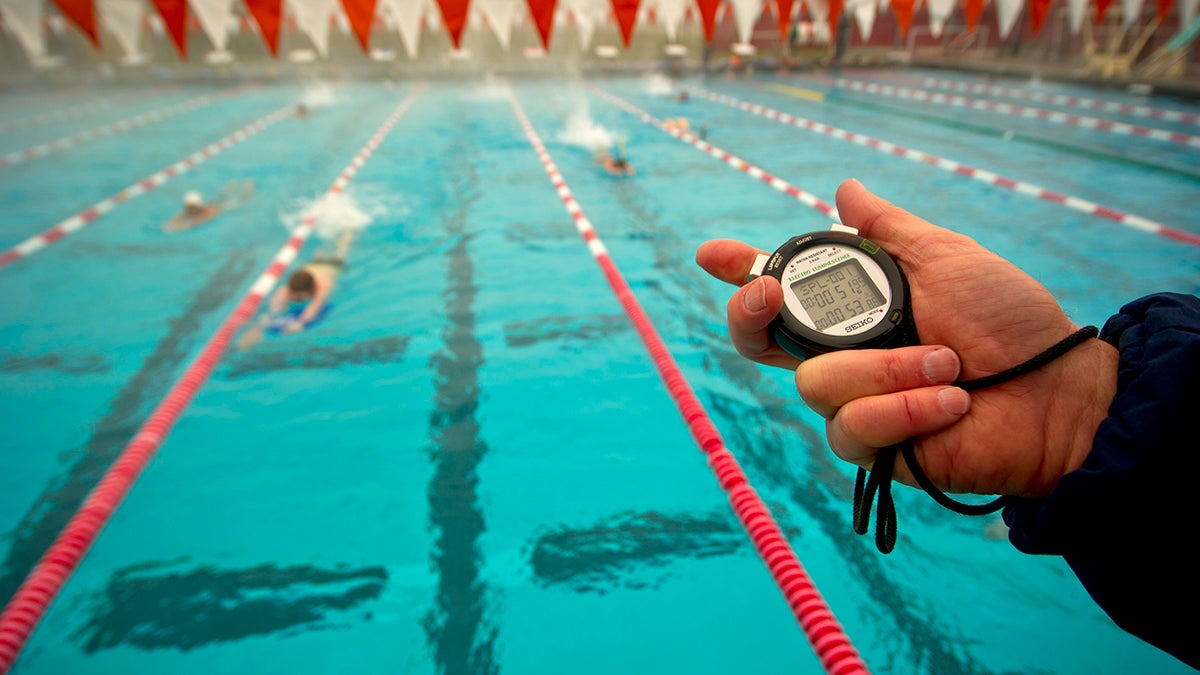 Swimmers, coach with timer