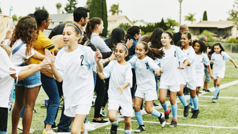 Youth girls soccer team high-fiving fans