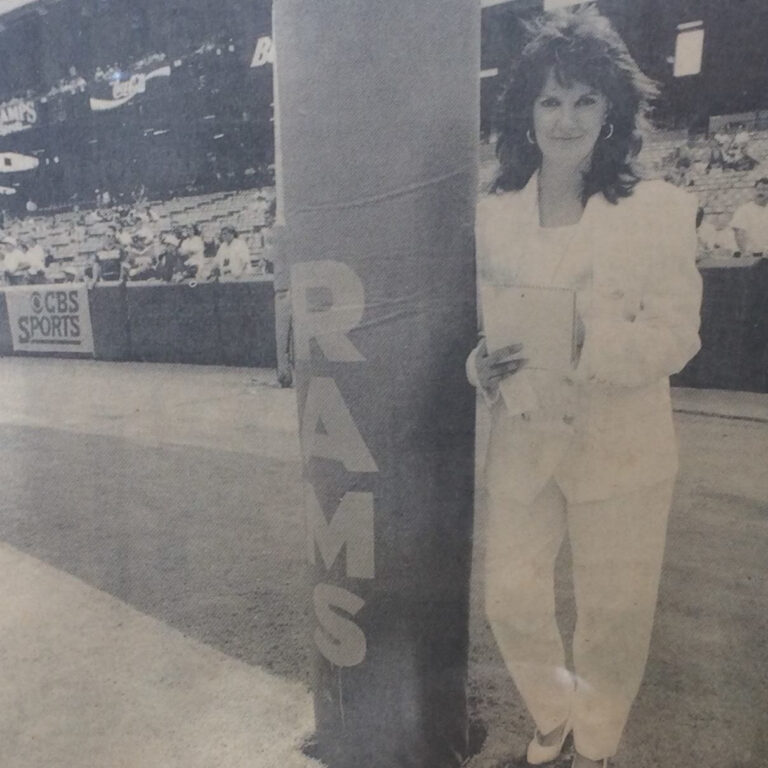 A black and white photo of Paola Boivin in front of the LA Rams goal post.