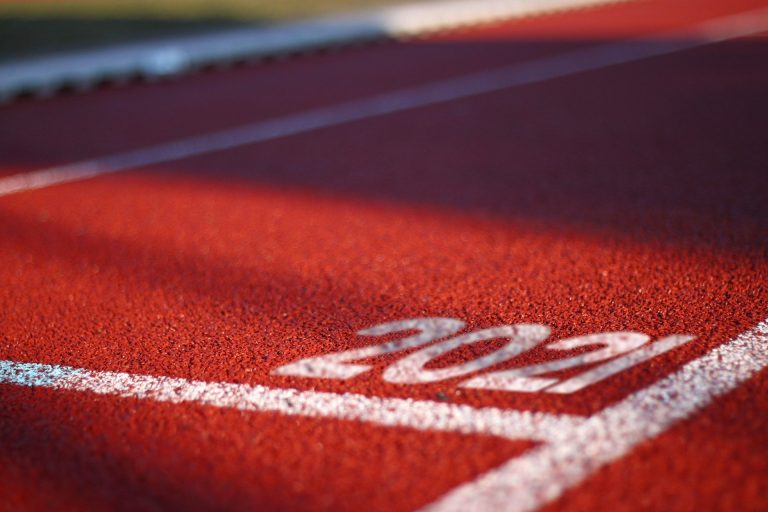 Close up of the lines on a running track, the typical lane numbers are replaced by '2021' (Photo via Pixabay)